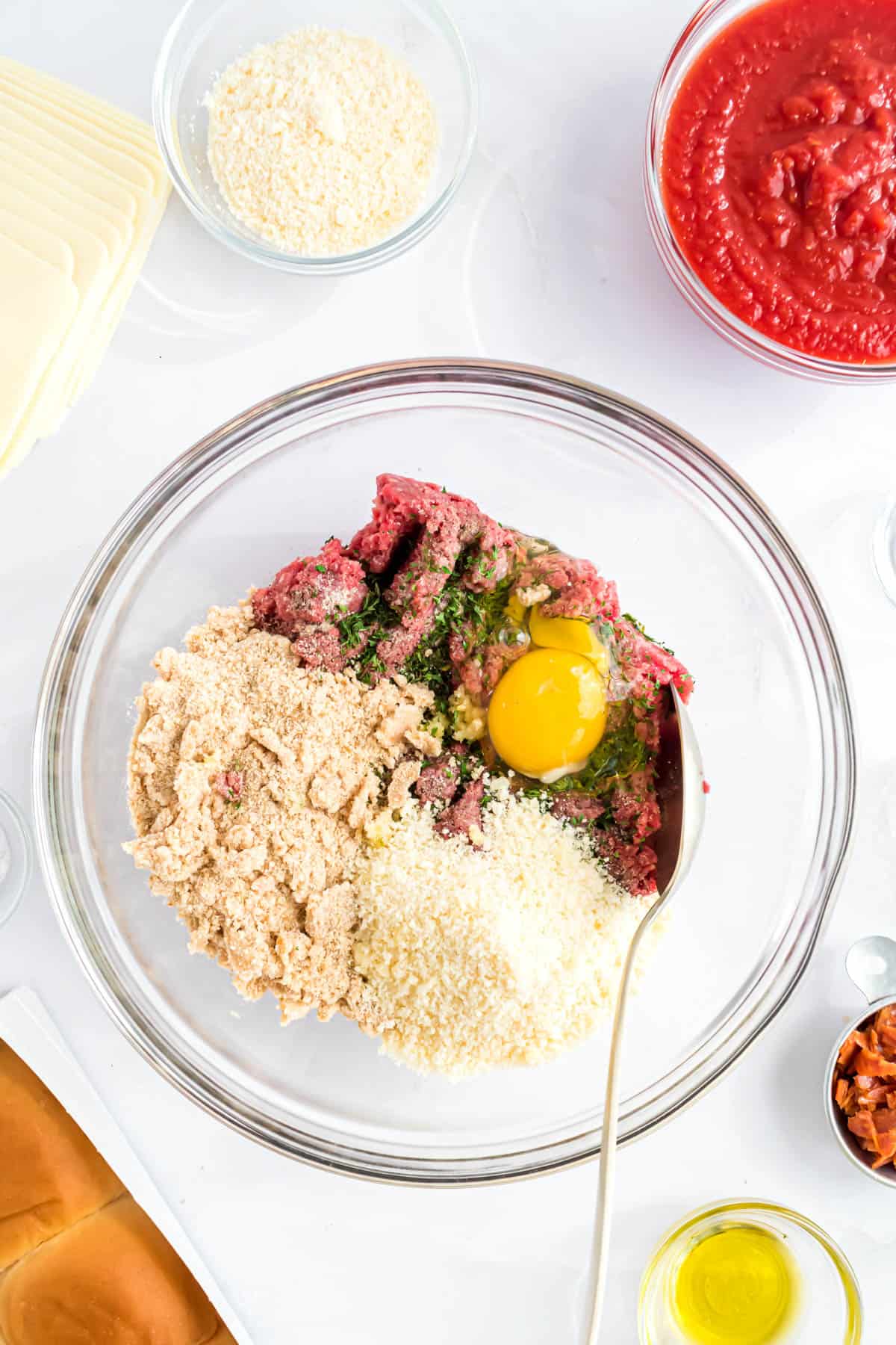 Ingredients for making meatballs in a glass bowl.