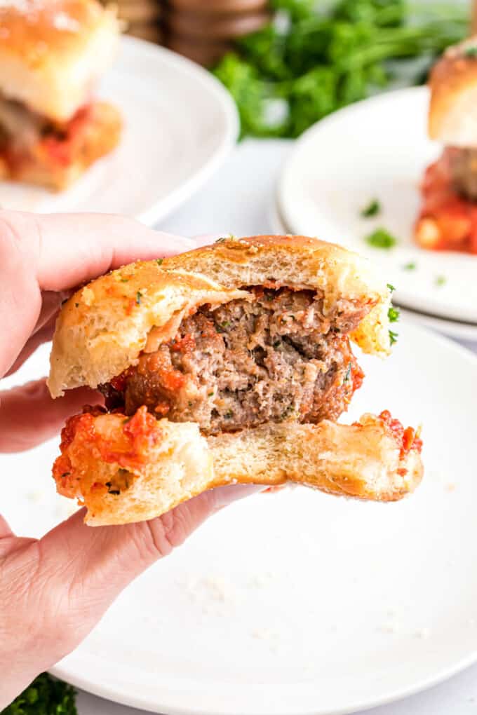 A meatball slider with a bite taken out of it.