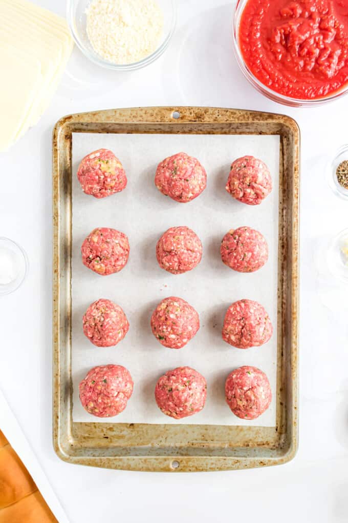 Meatball mixture shaped into balls on a baking sheet.