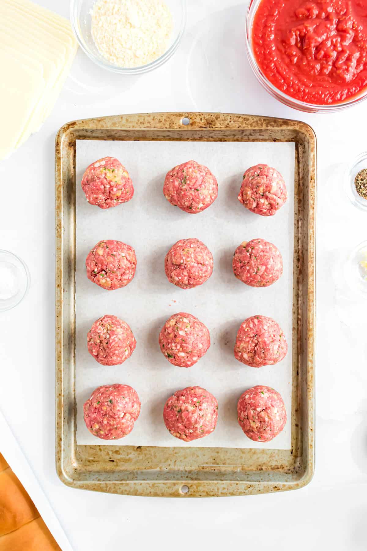 Meatball mixture shaped into balls on a baking sheet.