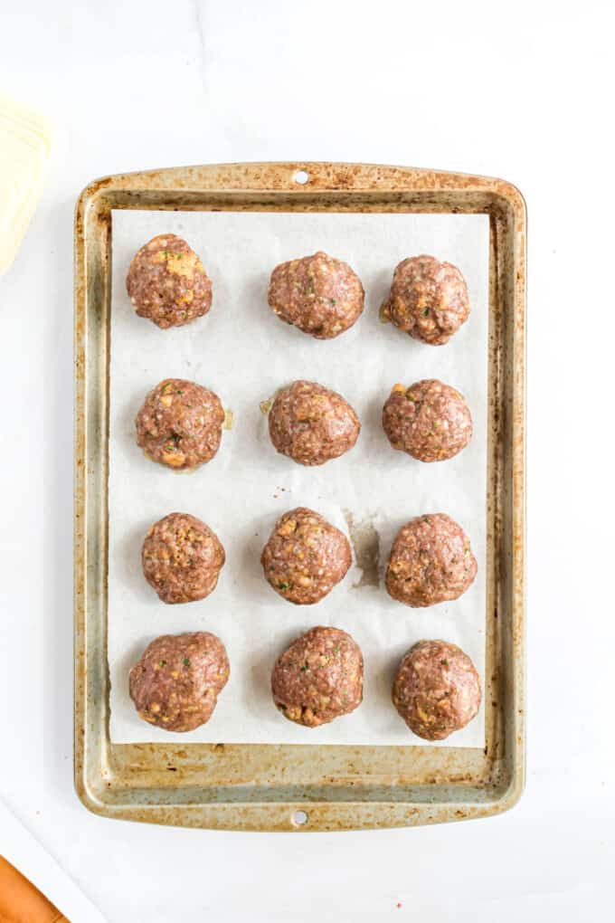 Baked meatballs on a baking sheet lined with parchment paper.