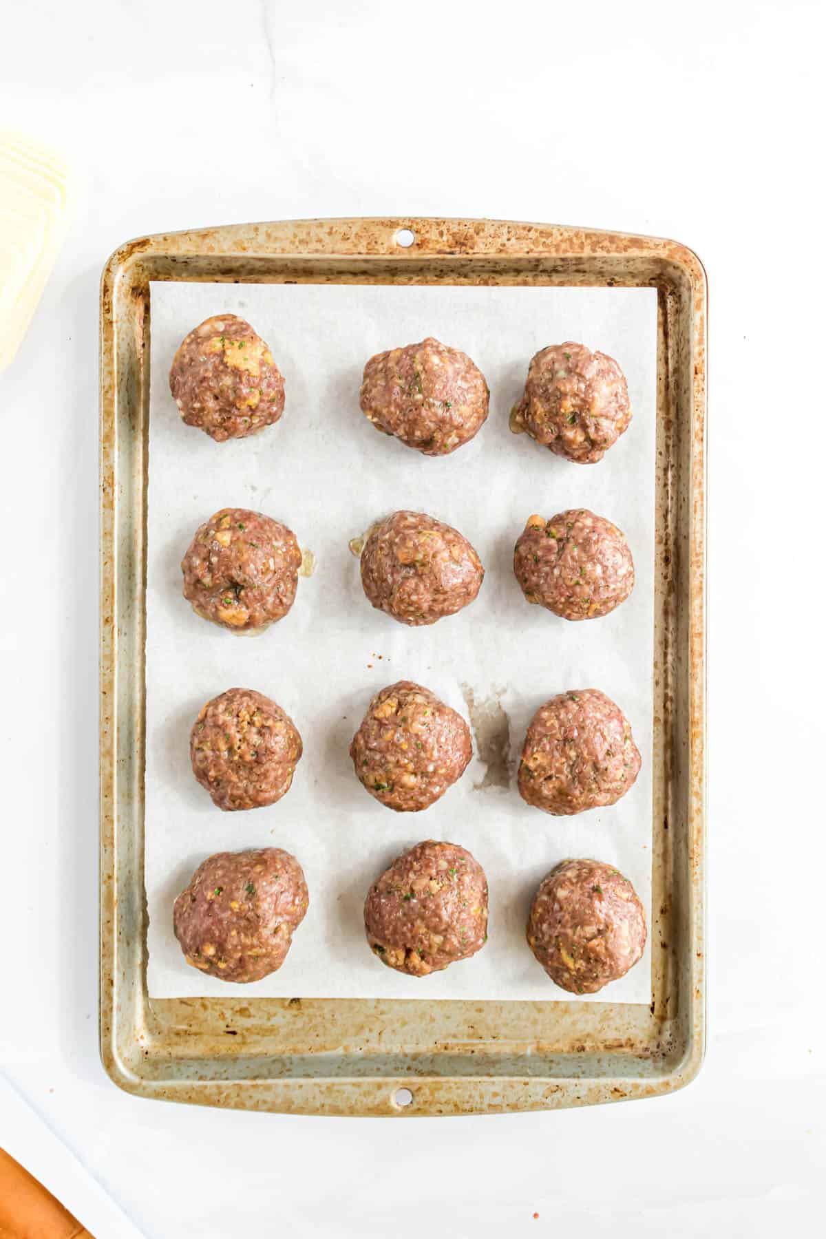 Baked meatballs on a baking sheet lined with parchment paper.