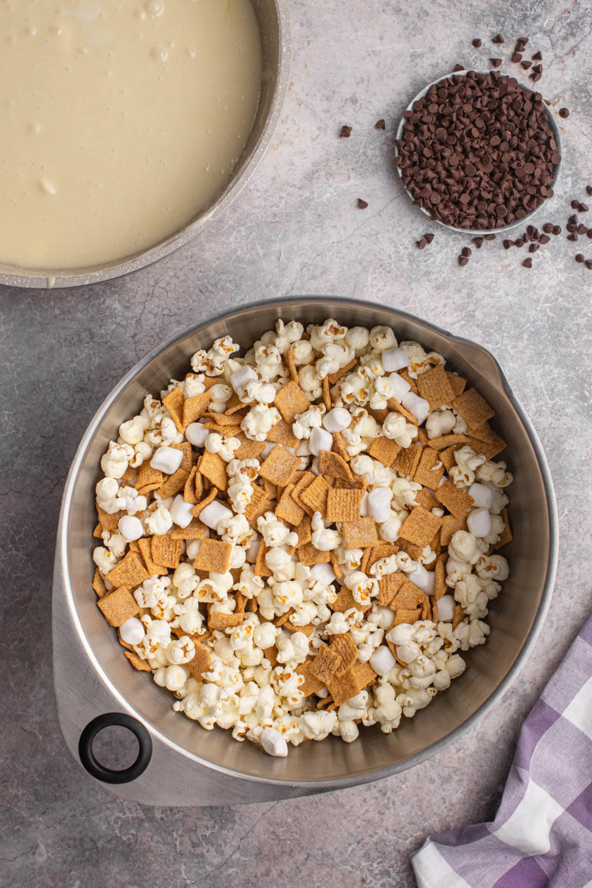 Combining popped popcorn and Golden Grahams cereal in a large mixing bowl.
