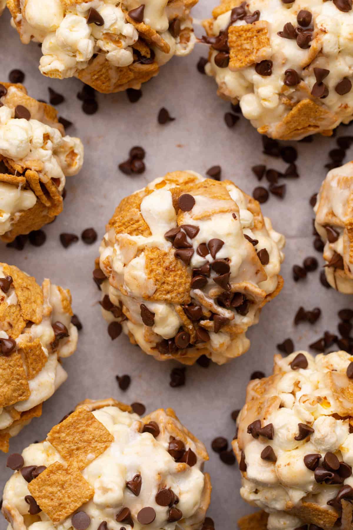 A close image of s'mores popcorn balls made with golden grahams cereal, popcorn, and mini chocolate chips.