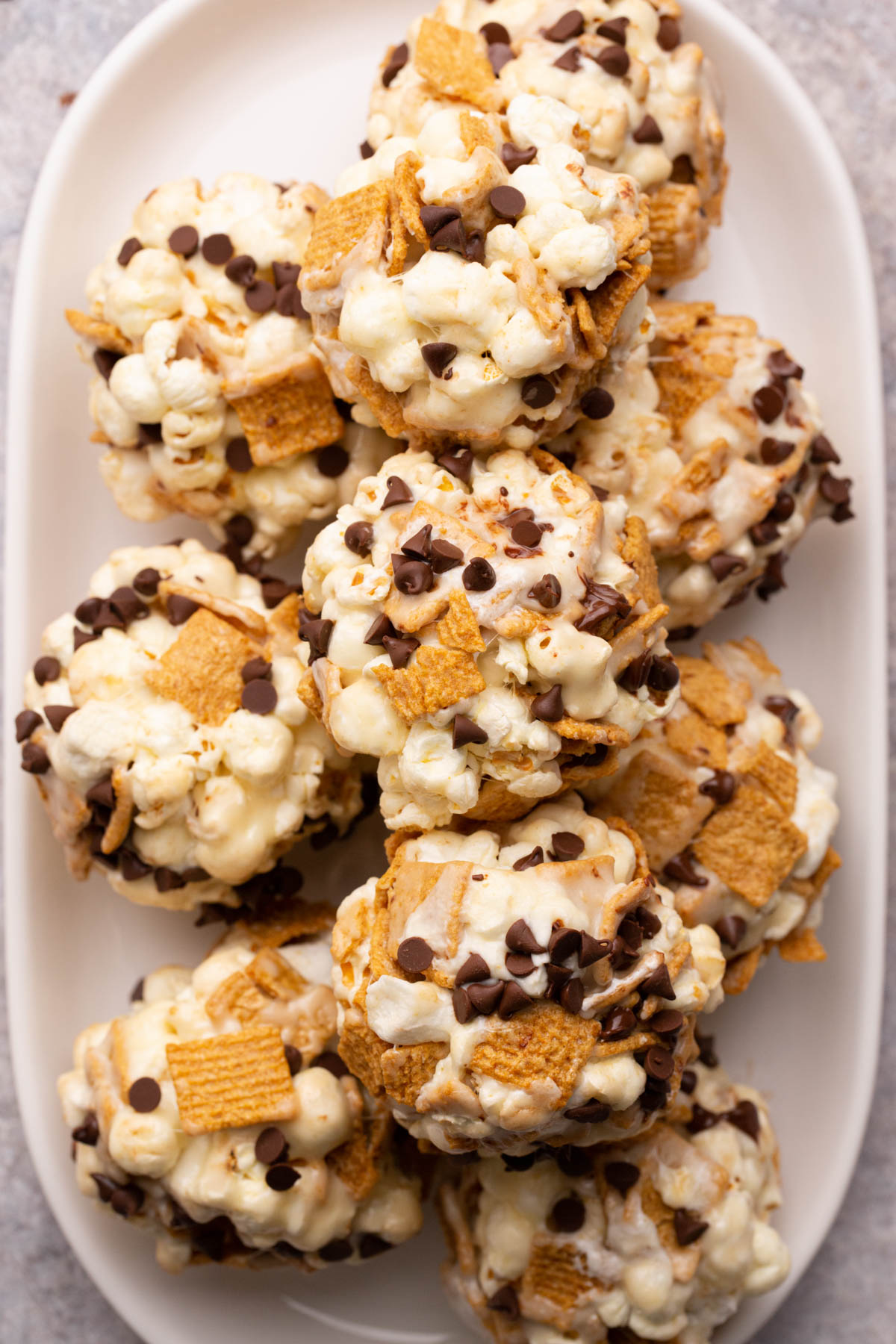 S'mores popcorn balls stacked on a white serving platter.