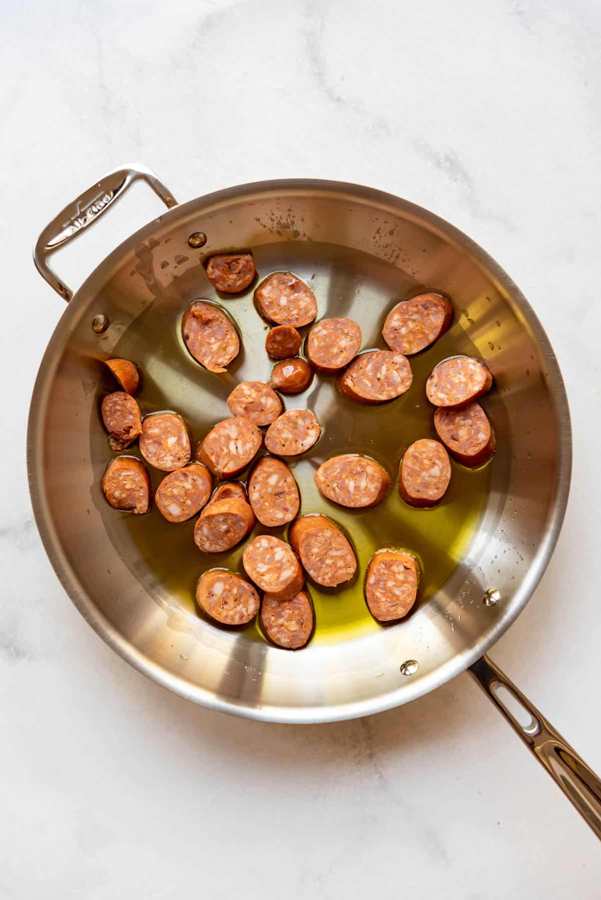 Searing sliced chorizo sausage in olive oil in a large skillet.