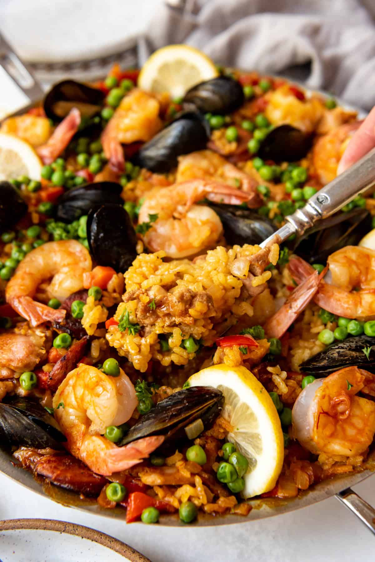 A spoonful of paella being lifted from the pan.