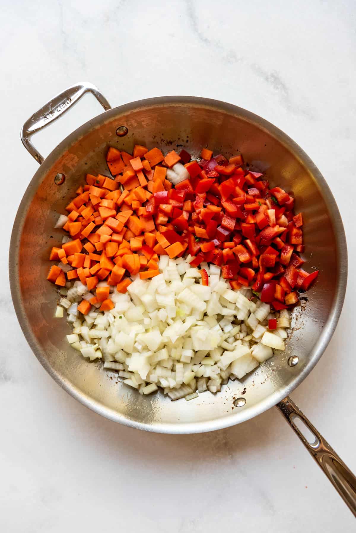 Sauteeing chopped onion, carrot, and red bell pepper in a large skillet.
