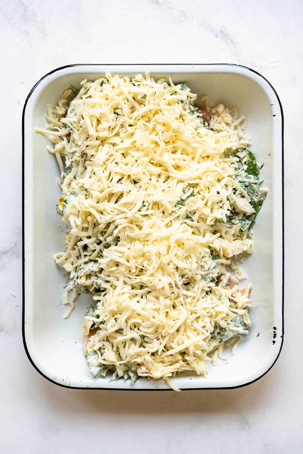 Shredded cheese sprinkled over chicken breasts topped with spinach artichoke mixture.