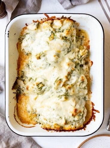 Baked spinach artichoke chicken in a baking dish.