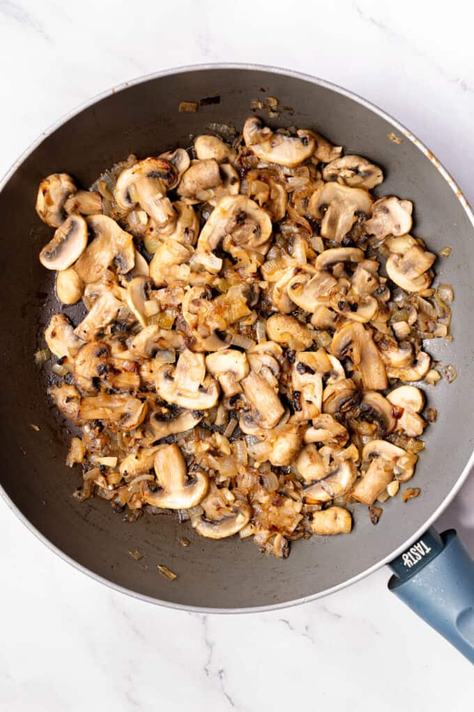 Sauteed onions and mushrooms in a large pan.