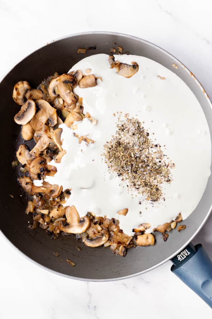 Adding heavy cream and spices to a pan of sauteed onions and mushrooms.