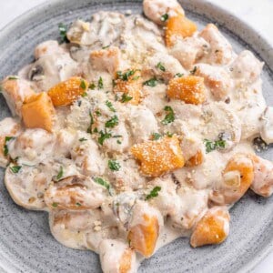 Homemade sweet potato gnocchi in a creamy mushroom sauce on a blue plate.