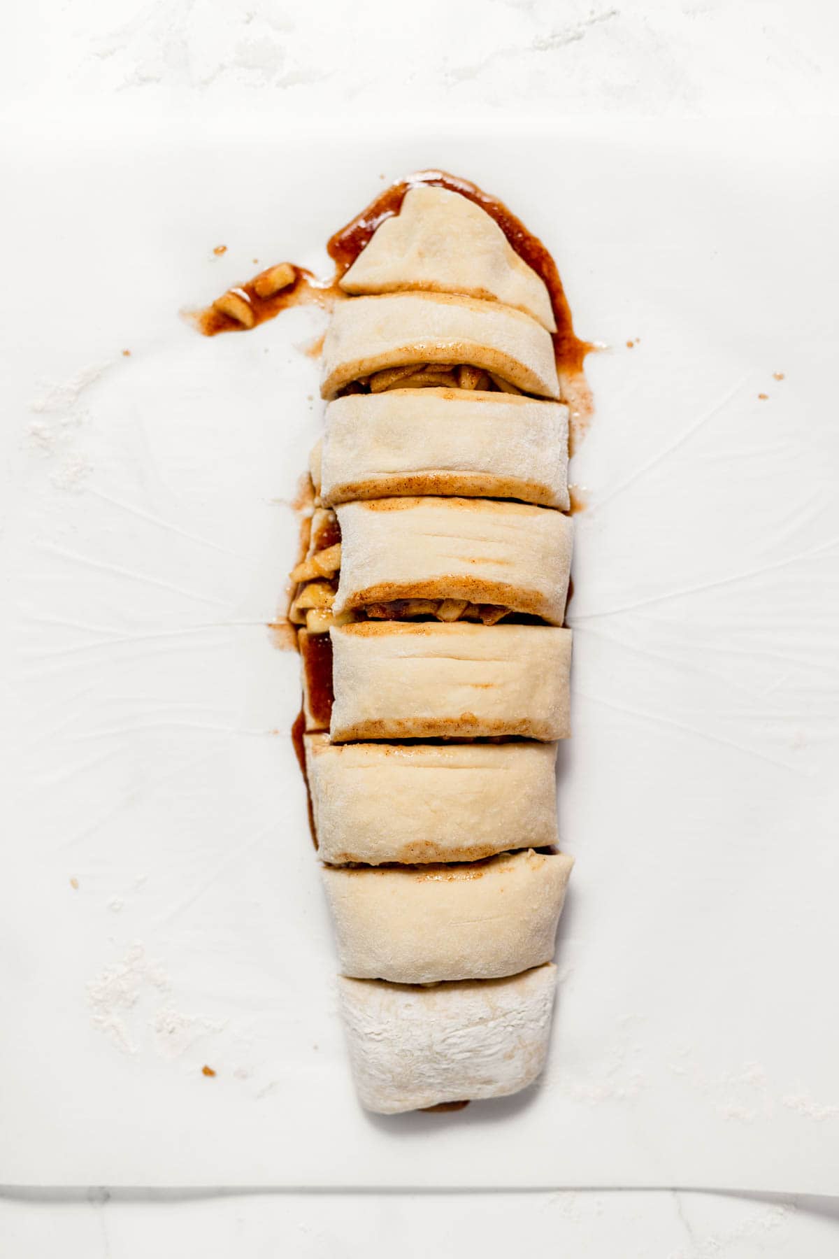 Cutting apple cinnamon rolls into individual rolls.