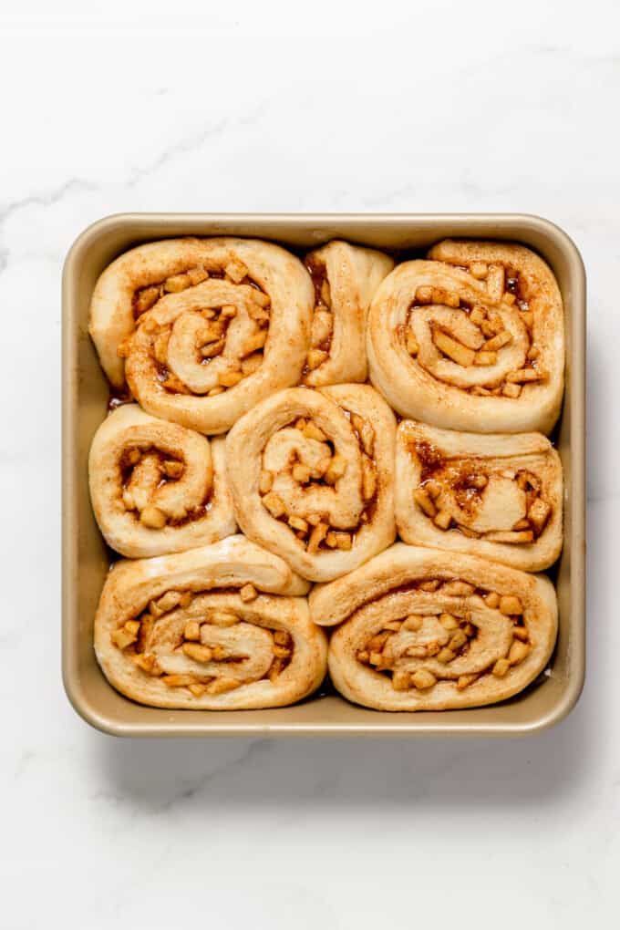 Puffy apple cinnamon rolls in a pan ready to bake.