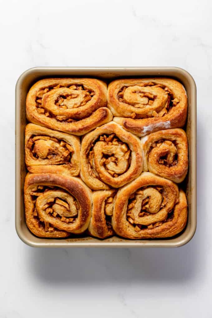 Baked apple cinnamon rolls in a square baking dish.