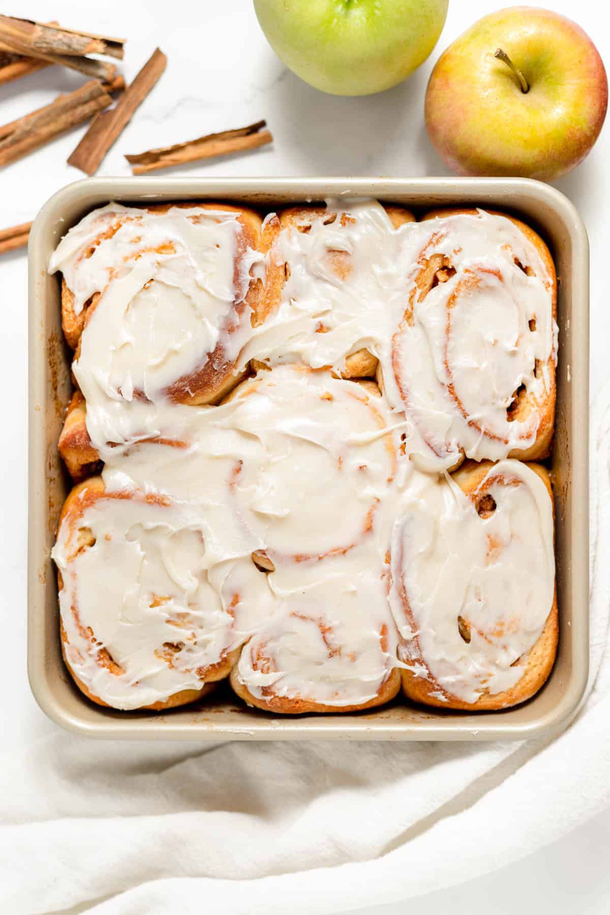 A square baking dish with apple pie cinnamon rolls.