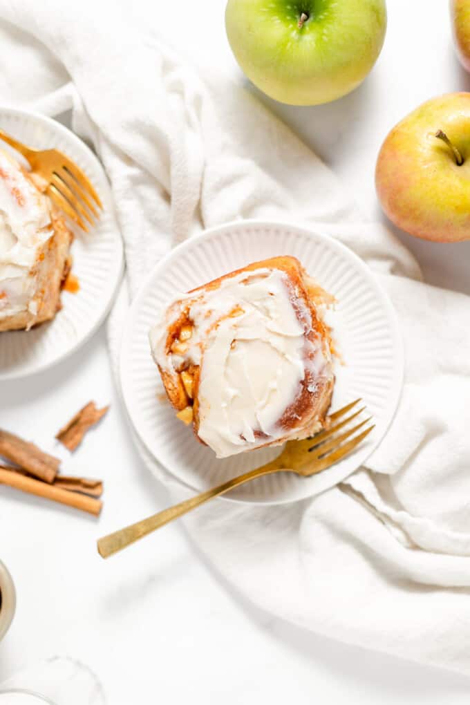 An overhead image of an apple cinnamon roll on a white plate.