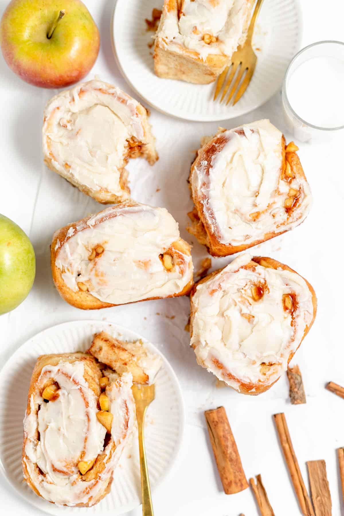 An overhead image of apple cinnamon rolls with apples and cinnamon sticks.