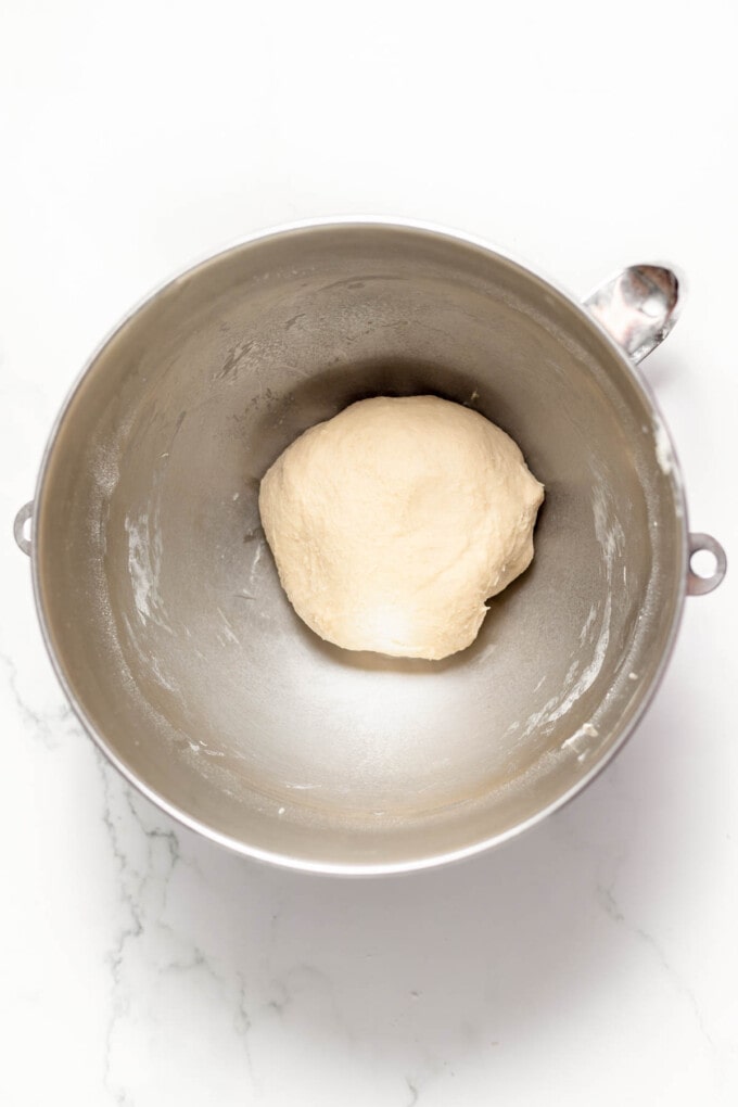 Kneaded dough in a large metal bowl.