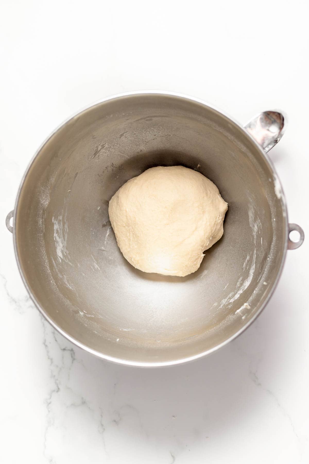 Kneaded dough in a large metal bowl.