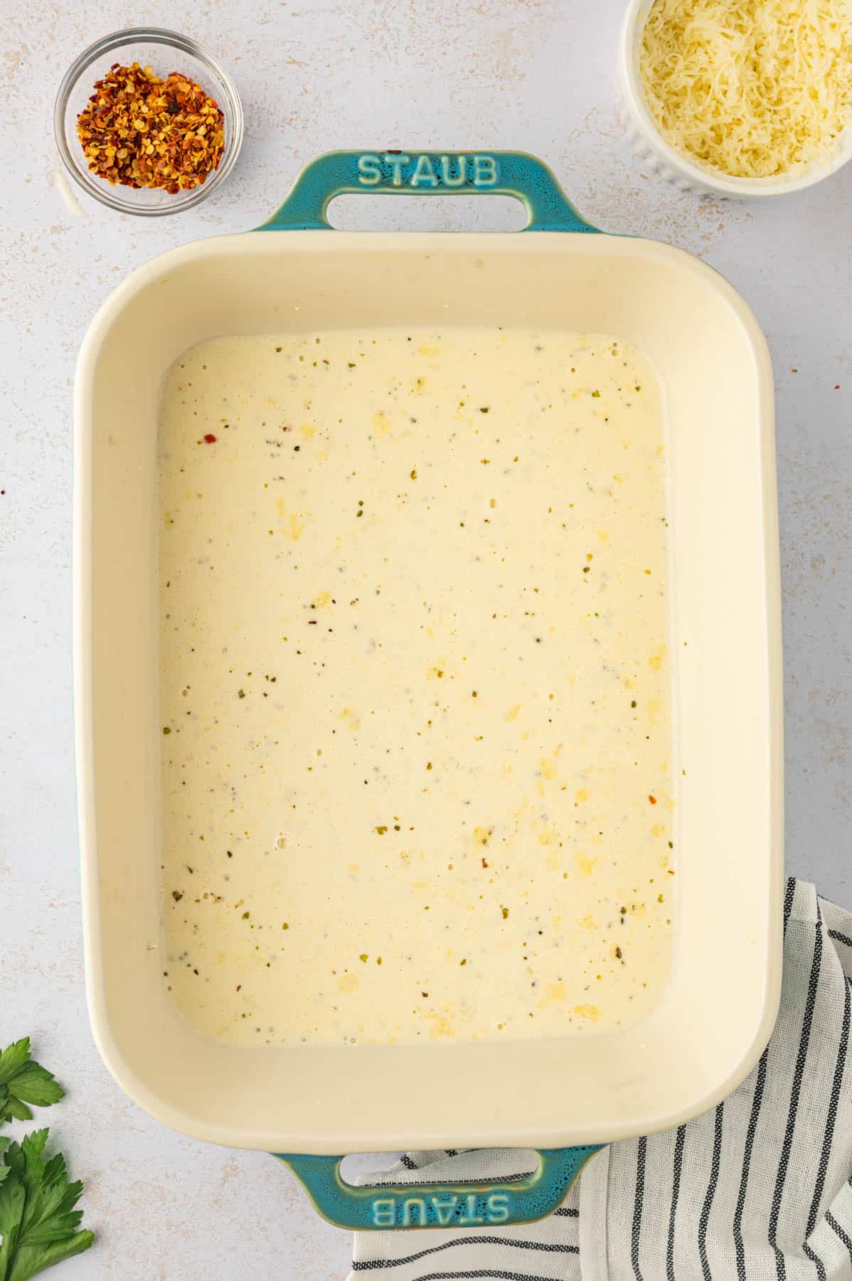A layer of alfredo sauce in the bottom of a casserole dish.