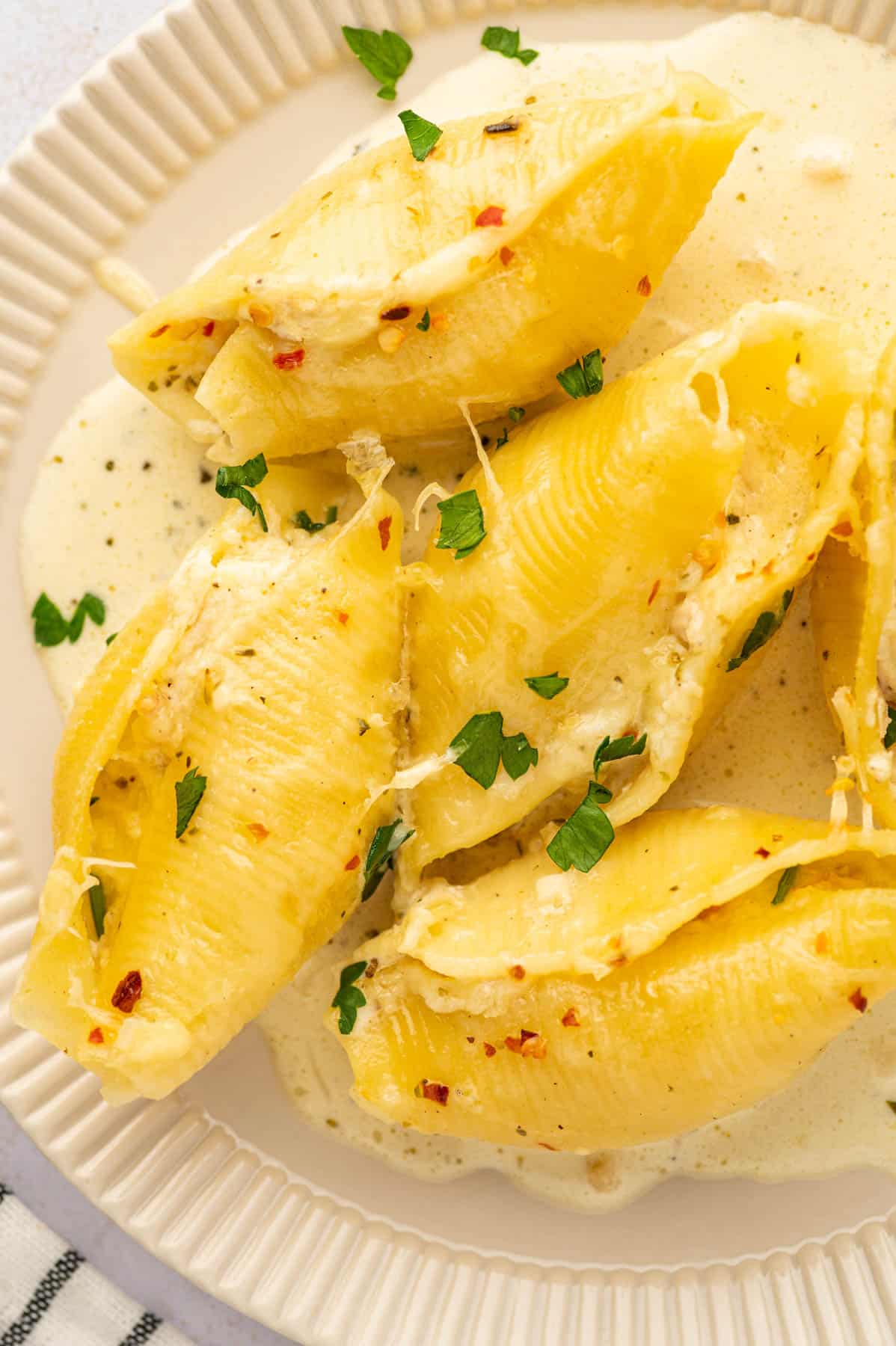 A close overhead image of chicken ricotta cheese stuffed shells on a plate.