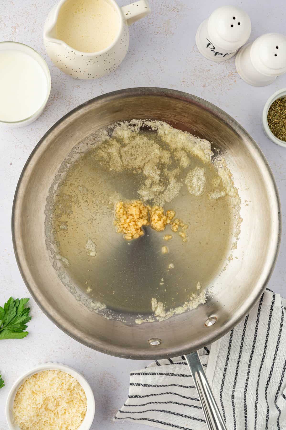 Cooking minced garlic in a pan with butter.