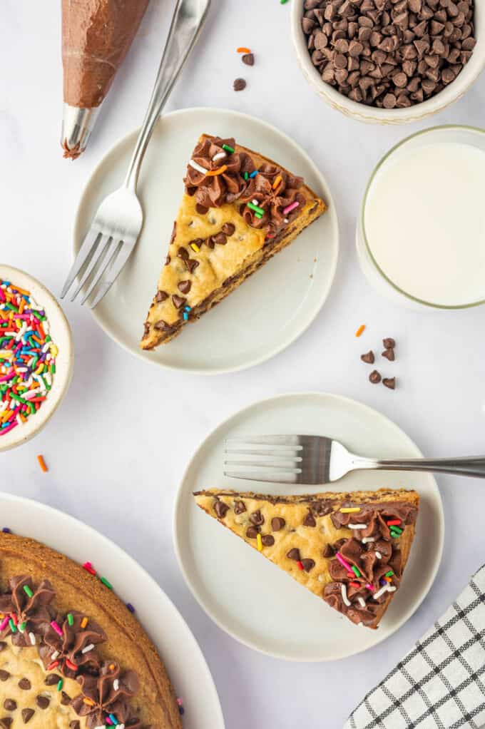 An overhead image of slices of chocolate chip cookie cake on white plates with forks.