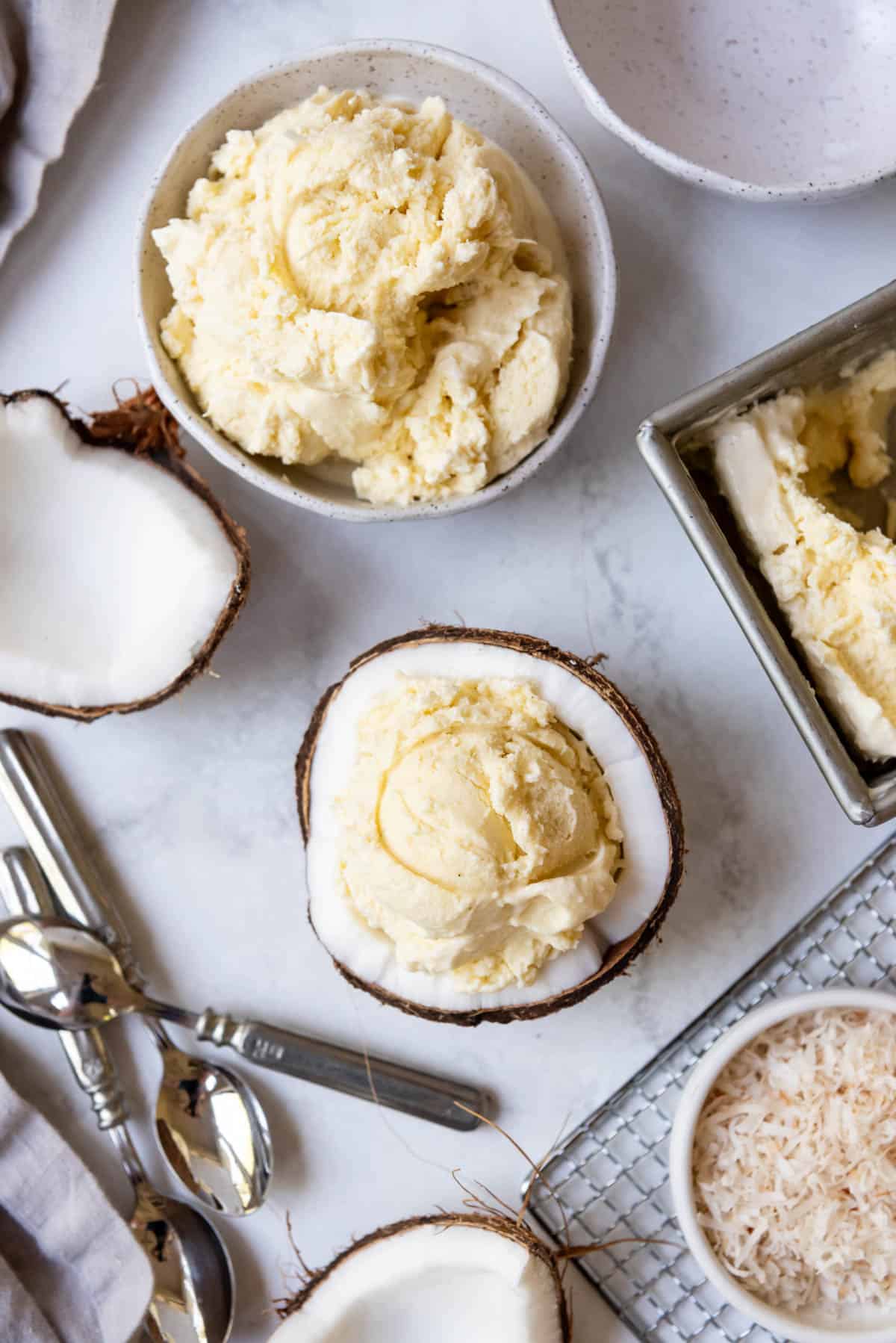 Scoops of coconut ice cream in a bowl and half a coconut.