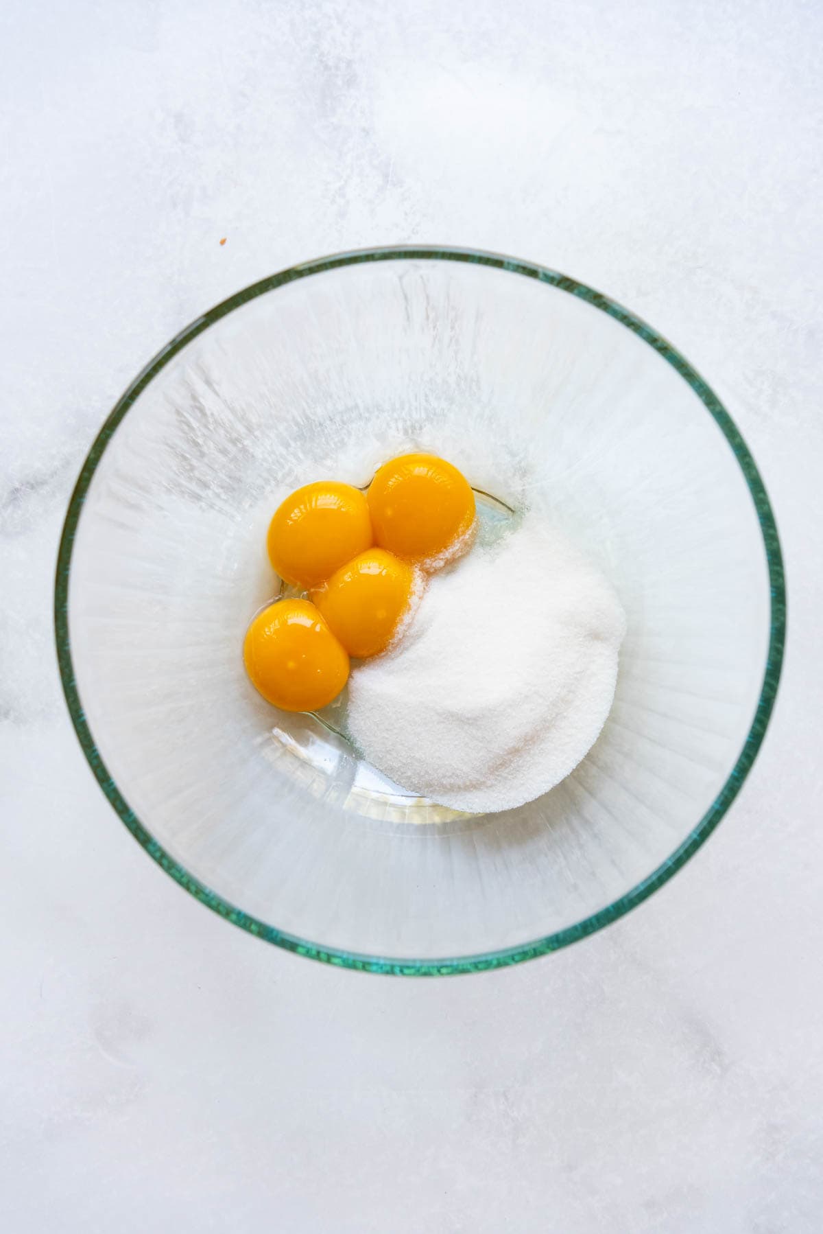 4 egg yolks and granulated sugar in a large glass bowl.