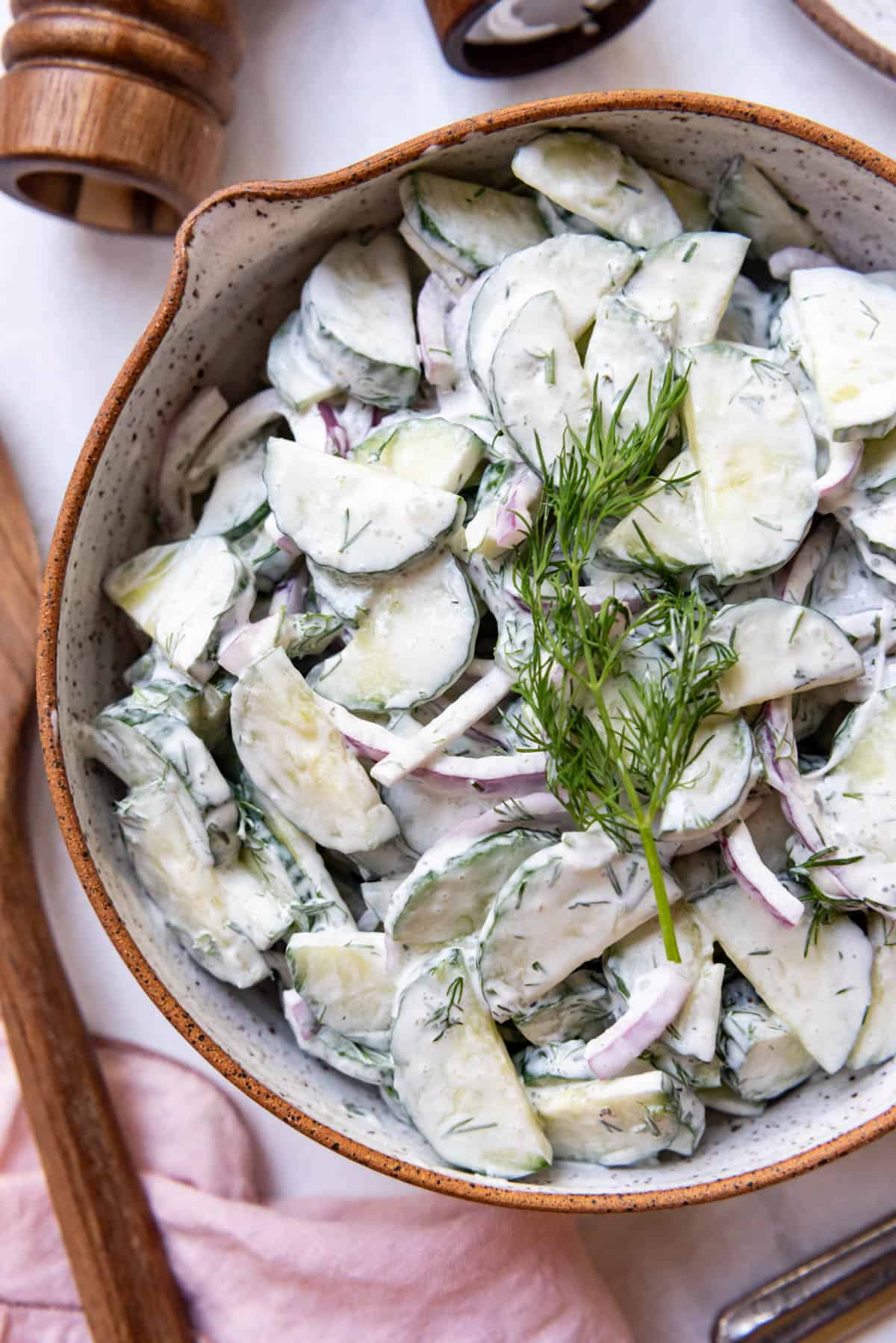 A close image of creamy German cucumber salad in a bowl.