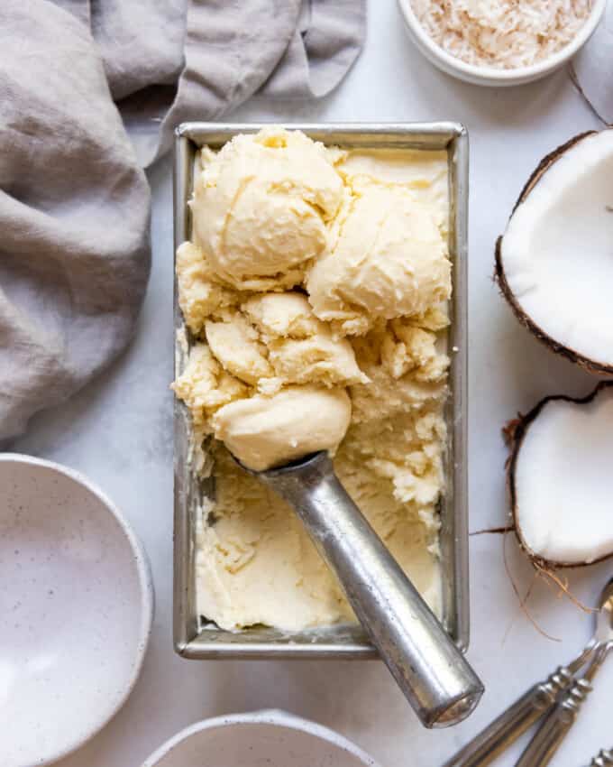 An overhead image of coconut ice cream scooped into balls in a bread pan.