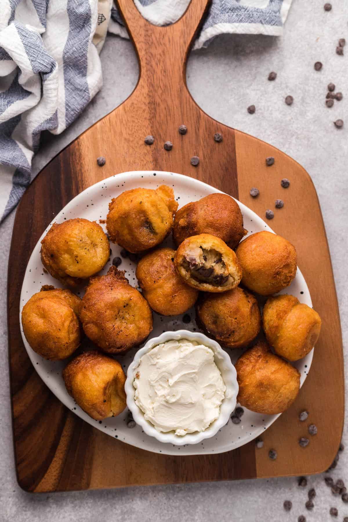 Fried cookie dough bites on a plate set on a wooden cutting board.