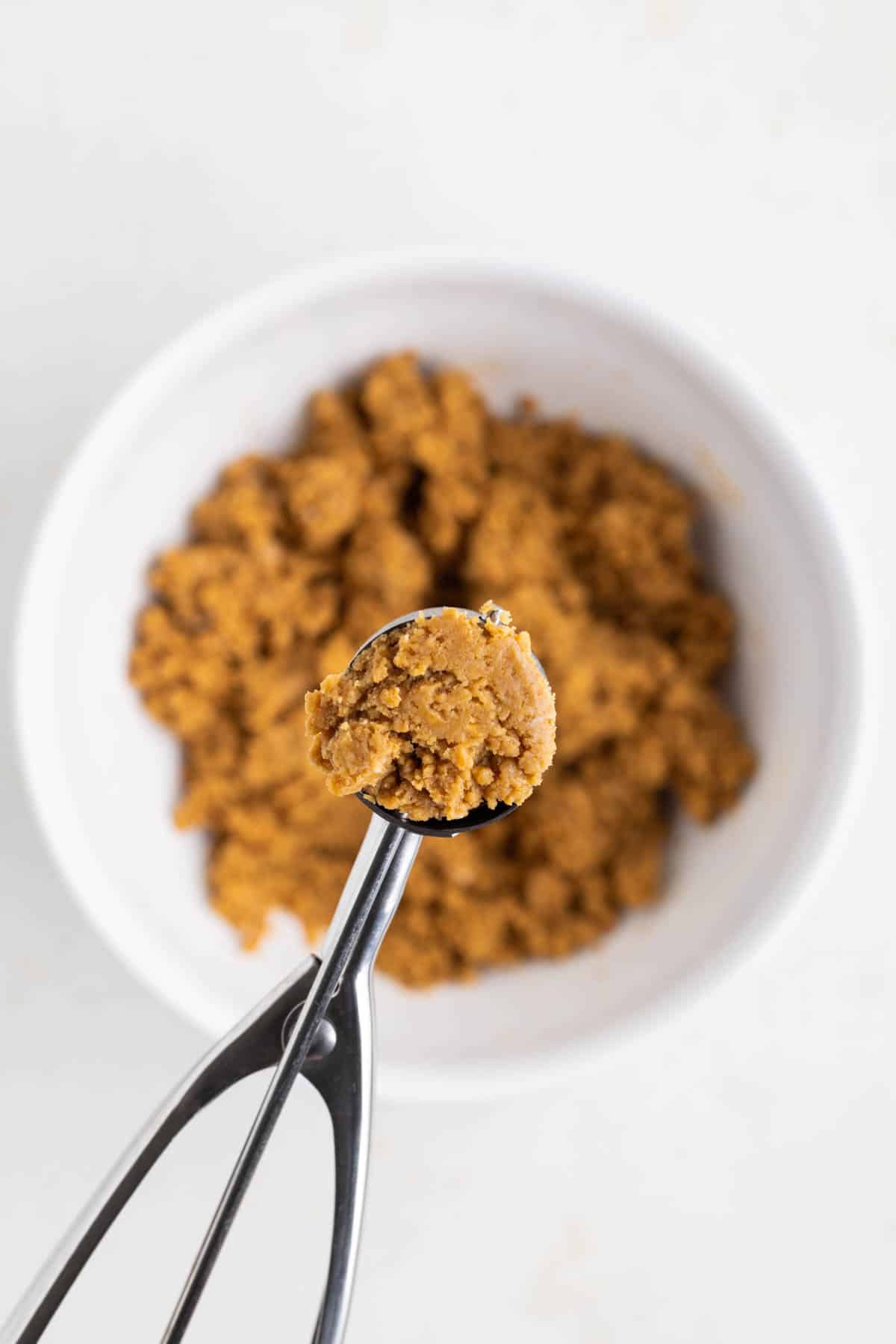 Using a small cookie scoop to shape gingerbread truffle centers.