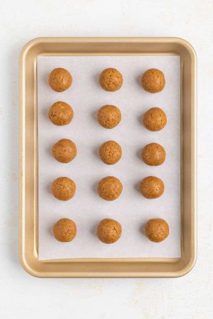 Gingerbread truffle centers rolled into balls on a baking sheet lined with parchment paper.