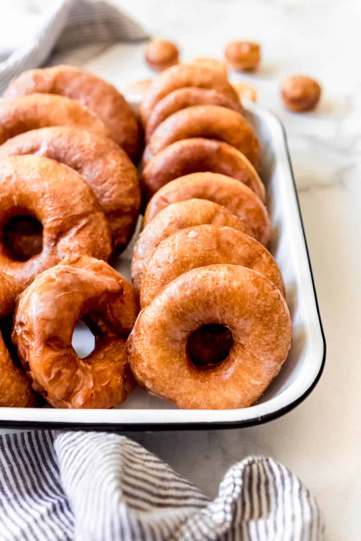 Yeast-raised donuts in a row in a baking dish.