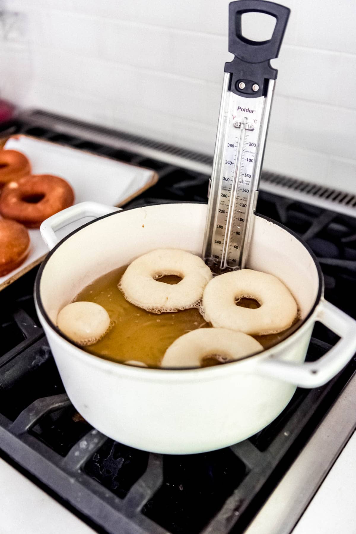 Frying yeast donuts in hot oil on the stovetop.