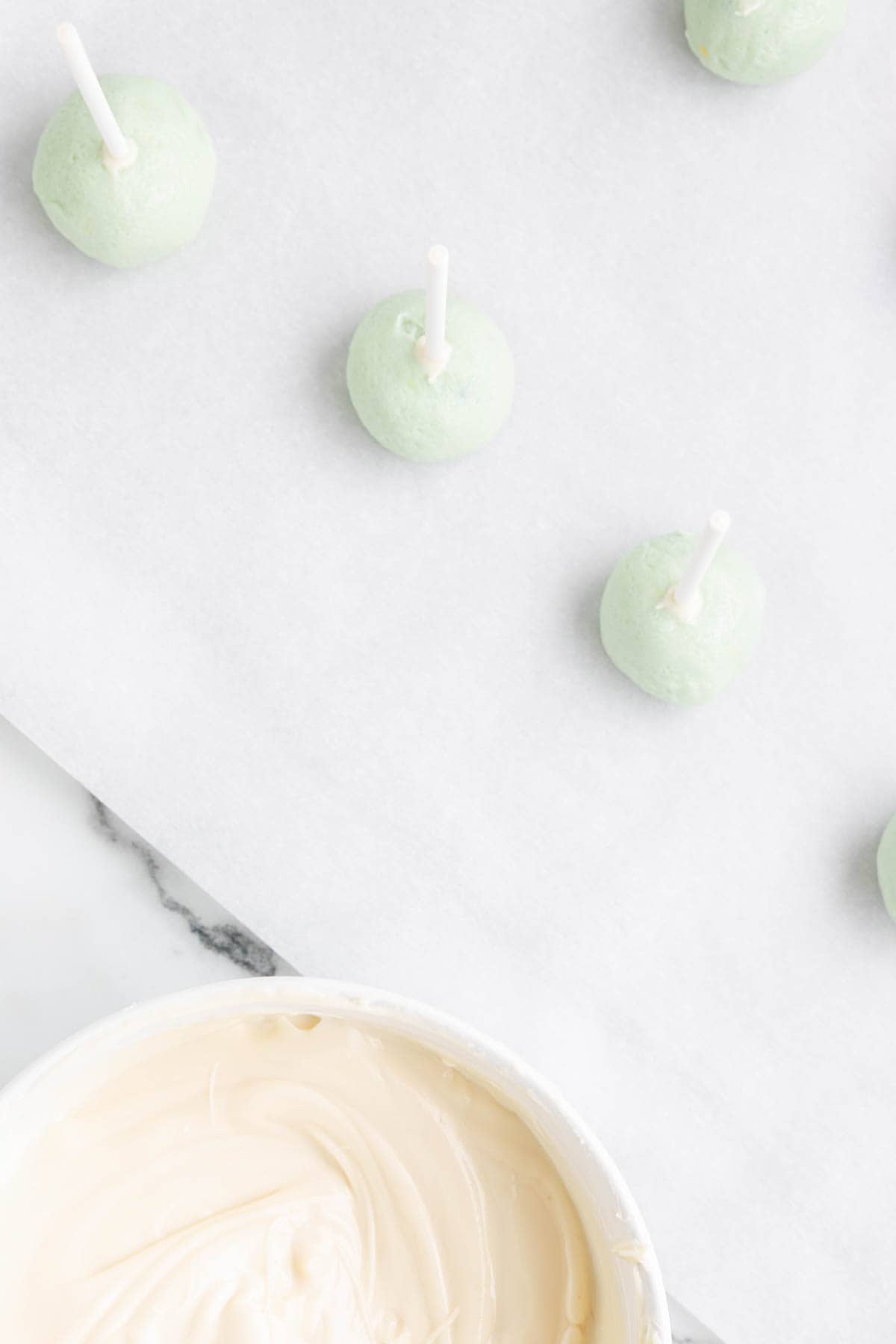 Dipping the bottom of sticks in melted white chocolate before pressing them into the chilled cookie cake pop centers.