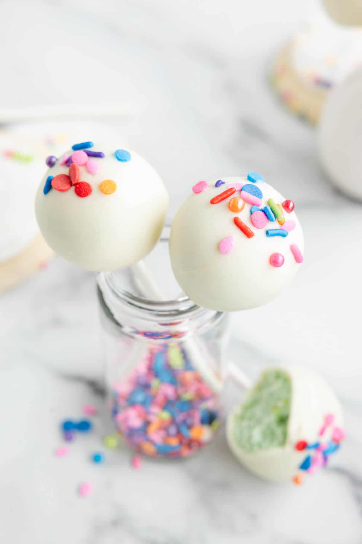 An overhead image of cookie cake pops decorated with sprinkles.