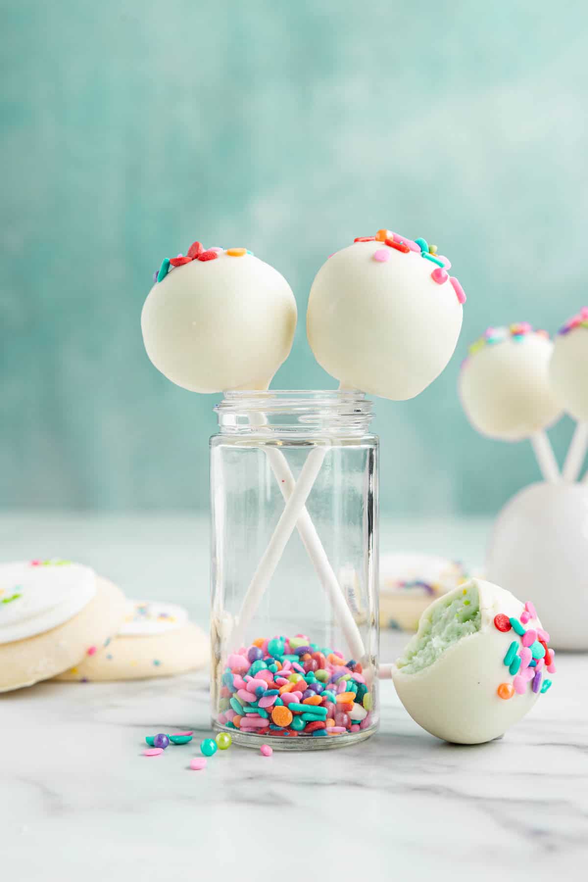 Lofthouse cookie cake pops covered in white chocolate in front of a blue background.
