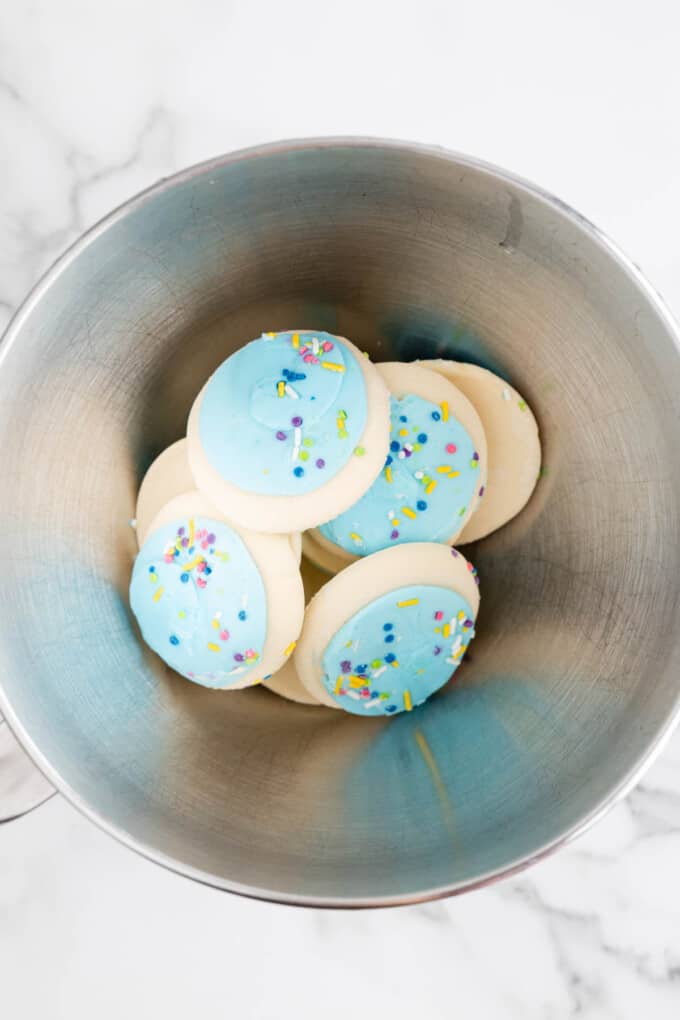 Lofthouse cookies with blue frosting in a mixing bowl.