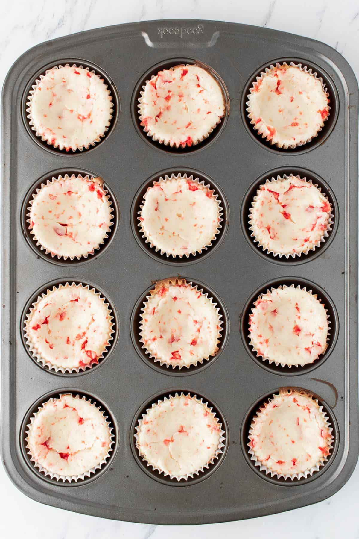 Baked mini white chocolate peppermint cheesecakes in a muffin pan.