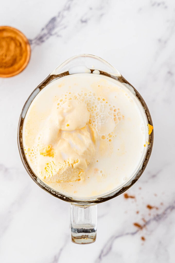 Combining pumpkin milkshake ingredients in a blender.