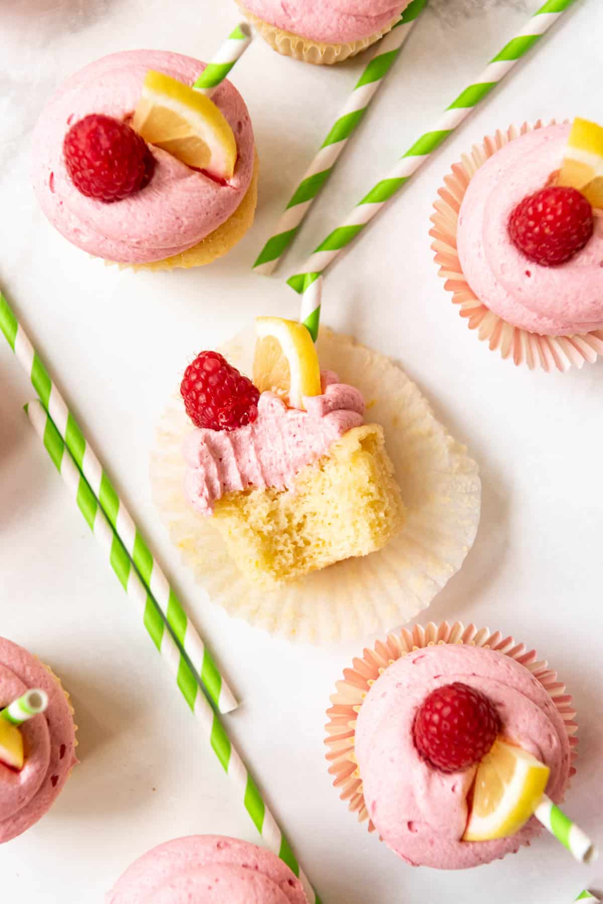 Top view of a Raspberry Lemonade Cupcake cutt in half on a white surface with other Raspberry lemonade cupcakes next to it.
