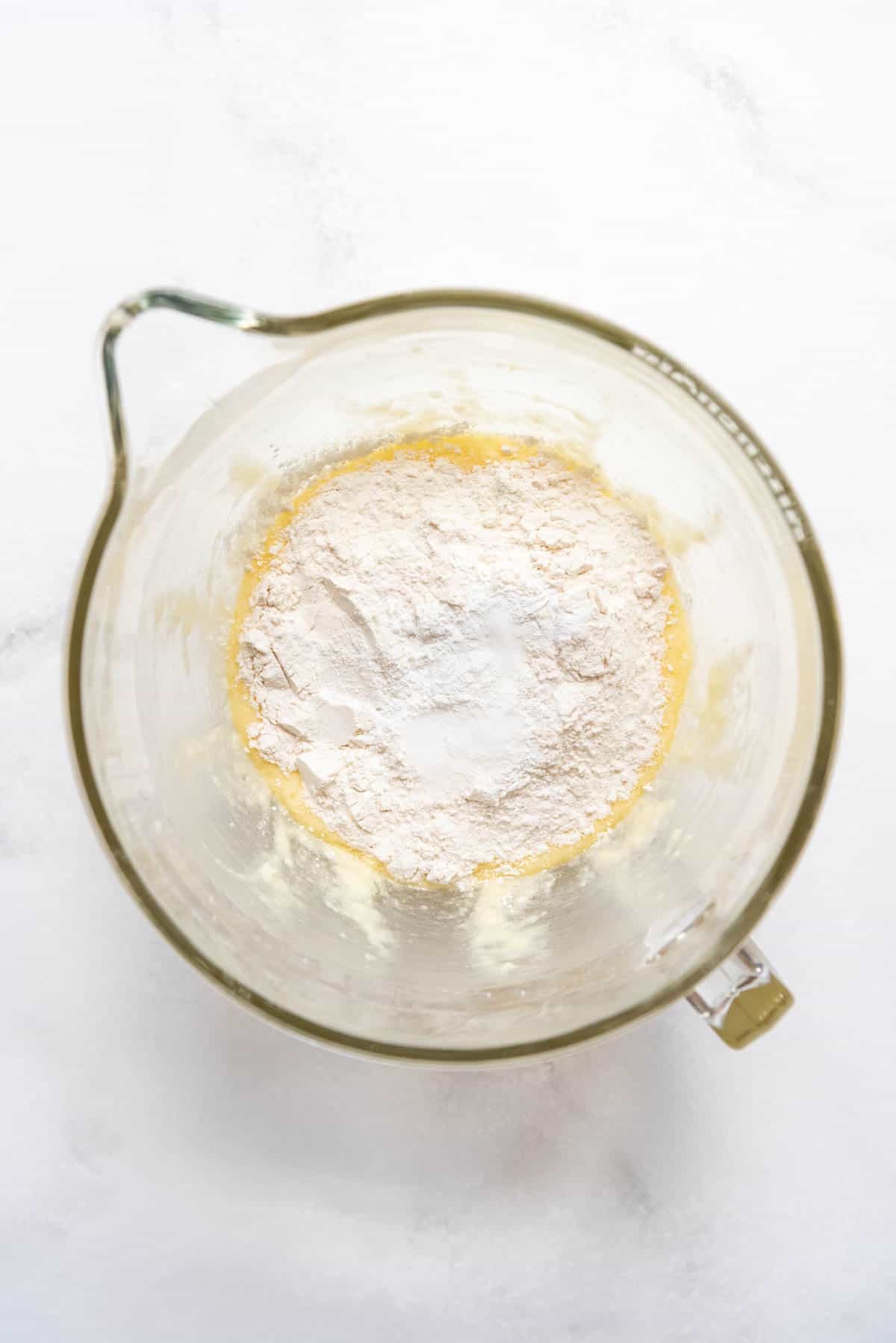 Top view of a glass mixing jug with a flour mixture on top.