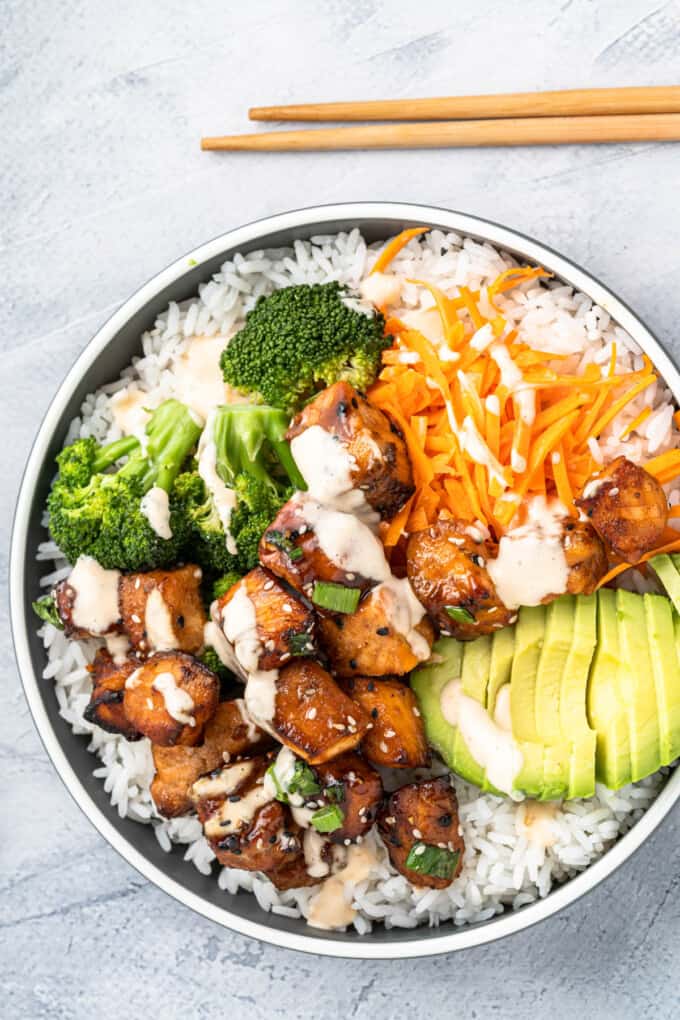An overhead image of a salmon bowl with veggies and rice.