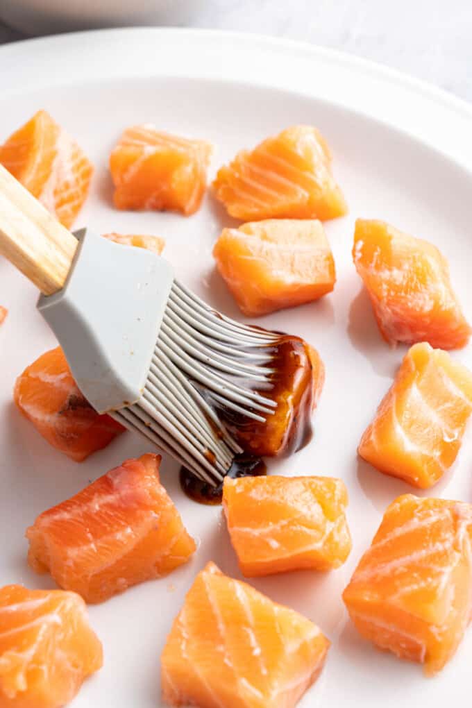 Brushing cubed salmon with a savory umami glaze.