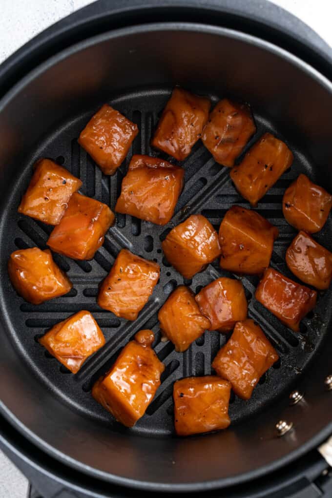 Arranging glazed salmon bites in an air fryer basket.