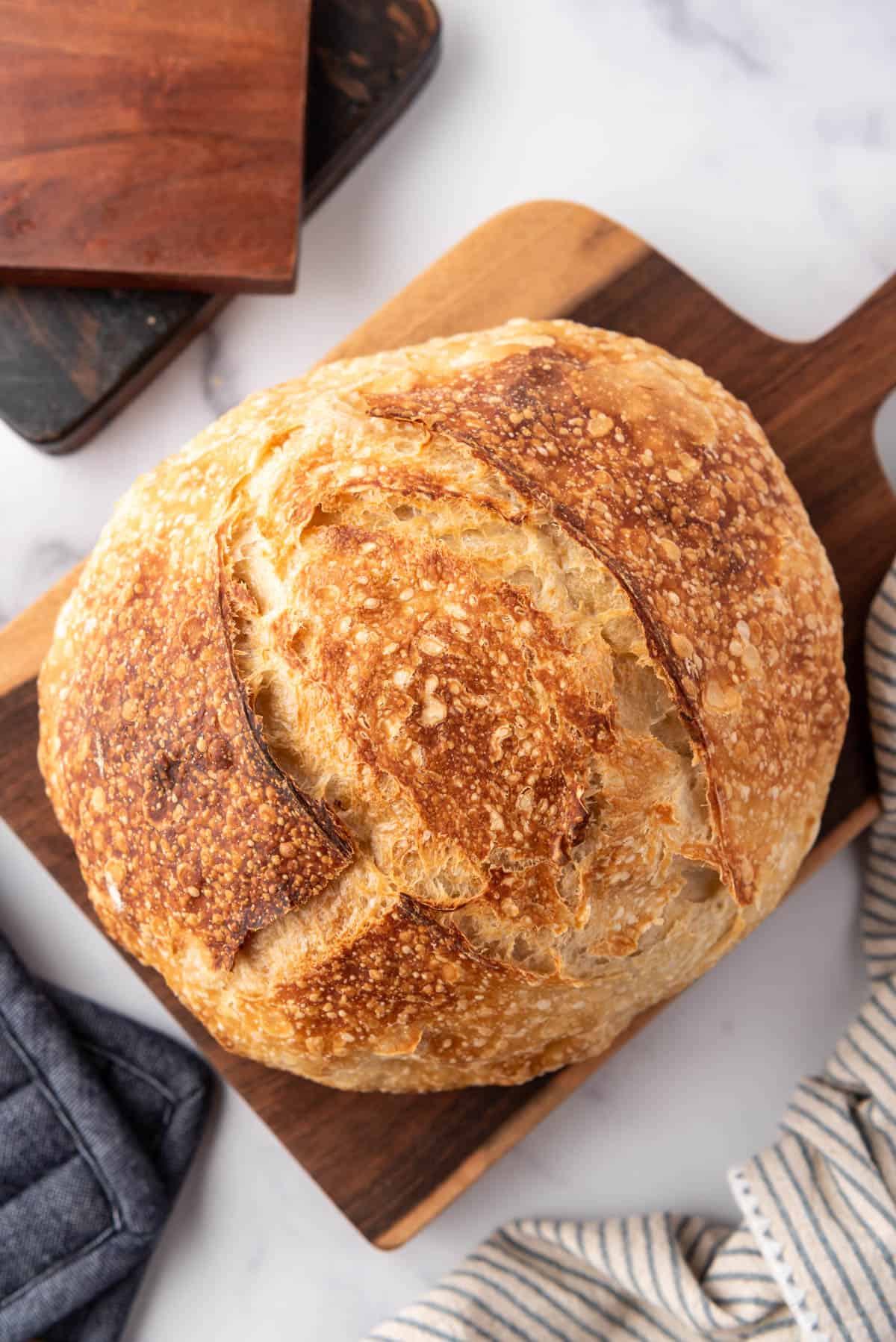 An overhead image of a loaf of sourdough bread on a wooden cutting board.